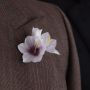 White Ixia boutonniere flower on lapel of brown suit, handmade by Fort Belvedere