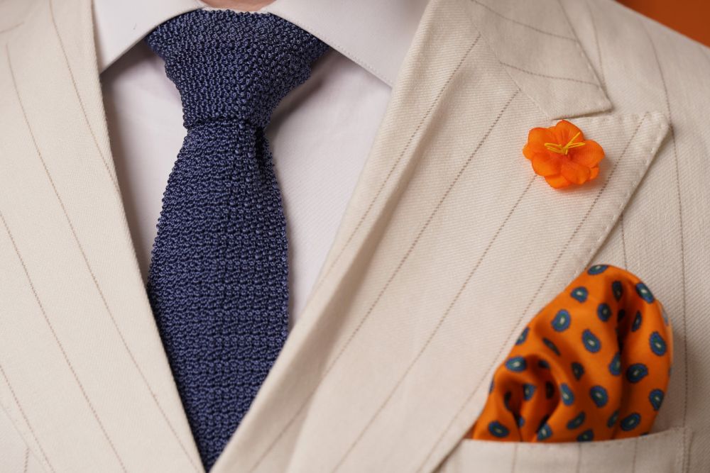 Orange Exotic Caribbean Boutonniere combine with a blue knit tie and orange paisley pocket square
