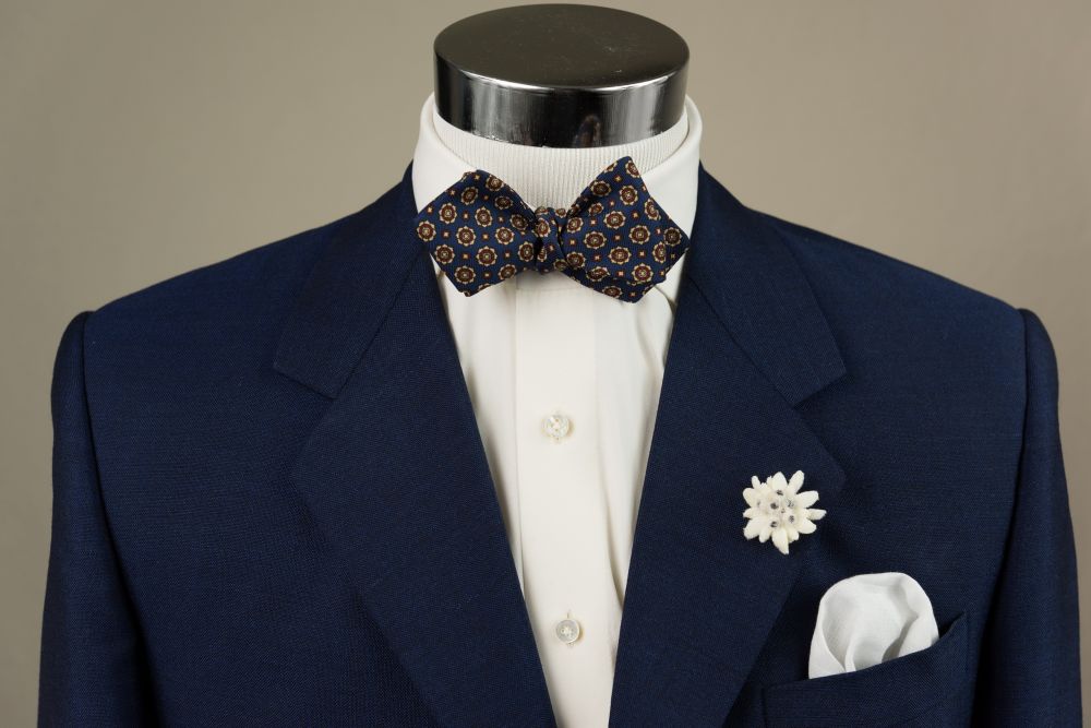 In Action Ancient Madder Silk Bow Tie in Blue with Buff & Red Micropattern paired with Edelweiss Boutonniere - Handmade by Fort Belvedere