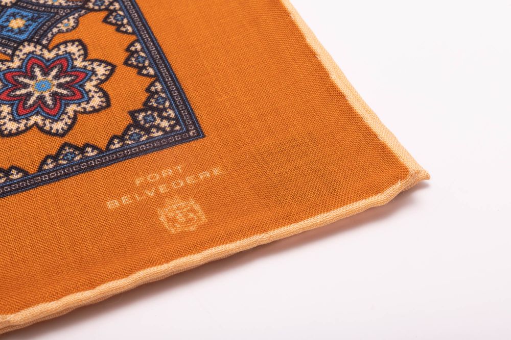 Edge of Antique Gold Ochre Silk Wool Pocket Square with Printed geometric medallions in beige, red and blue with cream contrast edge by Fort Belvedere