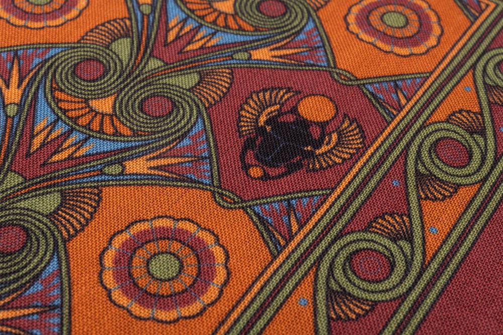 Fabric details of Brick Red Pocket Square Art Deco Egyptian Scarab pattern in green, orange, yellow, blue with green contrast edge by Fort Belvedere