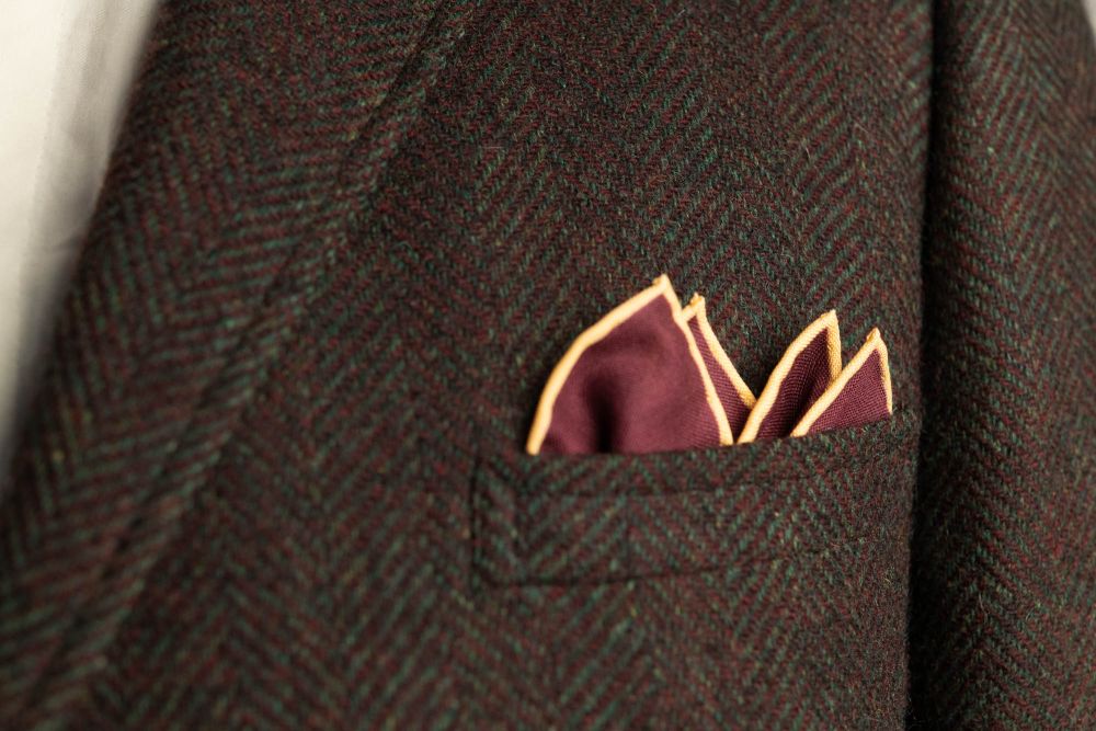 Burgundy Red Silk Wool Pocket Square with Printed geometric medallions in olive green, light blue, cream and orange with beige contrast edge by Fort Belvedere - Crown fold