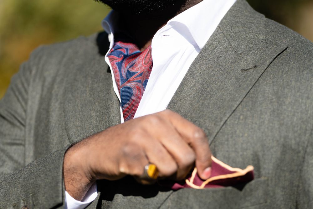 Ascot in Madder Silk with Red, Orange, Navy and Light Blue Paisley in white long sleeve and gray suit with burgundy red silk wool pocket square by Fort Belvedere
