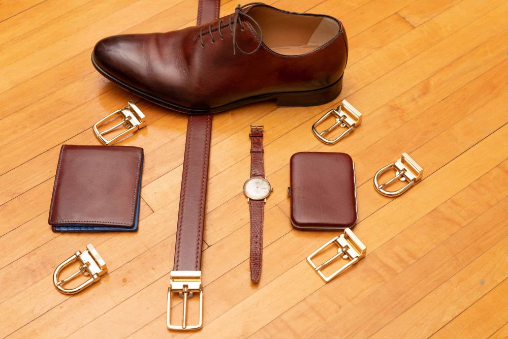 Gold Neville buckle on chestnut brown belt with other gold buckles and accessories