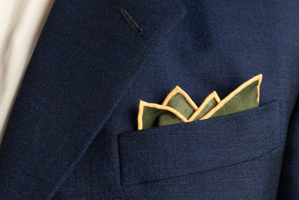 Moss Green Silk Wool Pocket Square with Printed geometric medallions in blue, red, black with eggshell contrast edge by Fort Belvedere - Crown fold