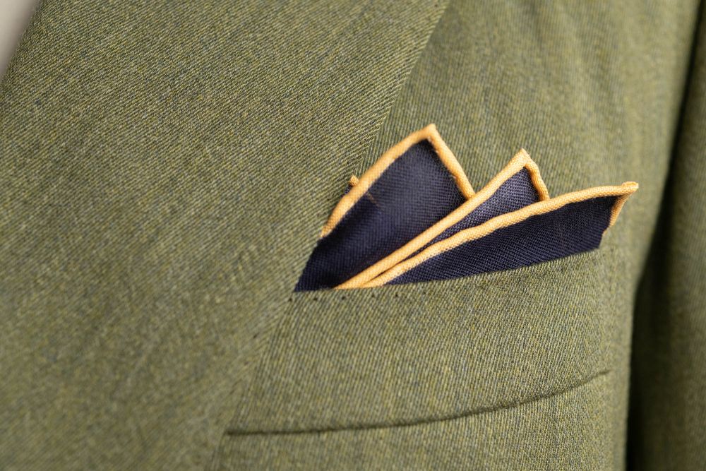 Navy Blue Silk Wool Pocket Square with Printed geometric medallions in green, blue and orange with off-white contrast edge - Fort Belvedere in olive green suite - Crown fold