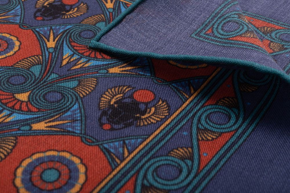 Close up edge of Sapphire Blue Pocket Square Art Deco Egyptian Scarab pattern in burnt orange, yellow, madder blue with teal contrast edge by Fort Belvedere 
