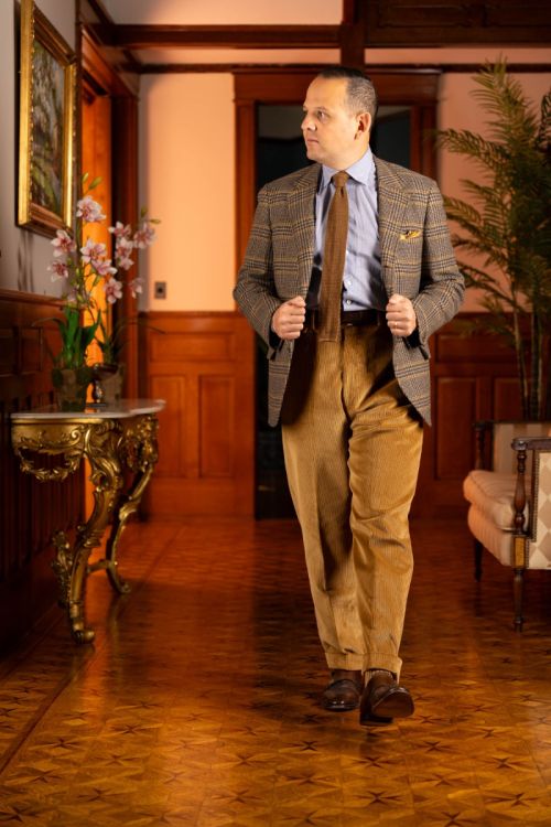 Raphael wearing a brown and yellow checked jacket paired with the Camel corduroy trousers. 