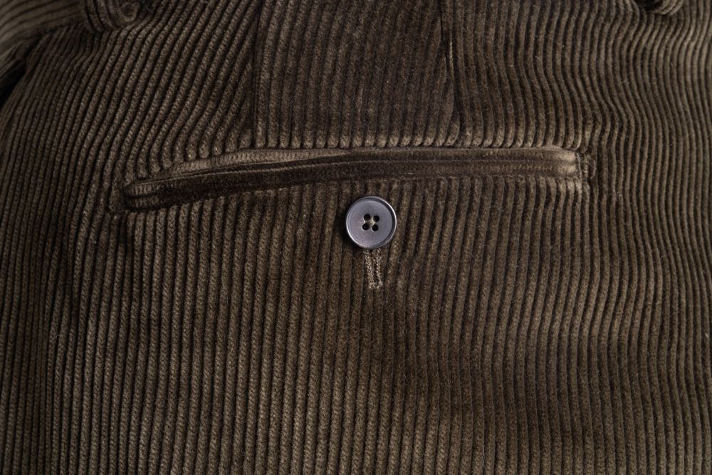 Close up view of the back pocket of the Dark Olive Corduroy trousers. 
