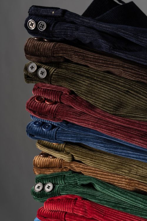Up close view featuring the buttons of corduroy trousers including the maroon one. 