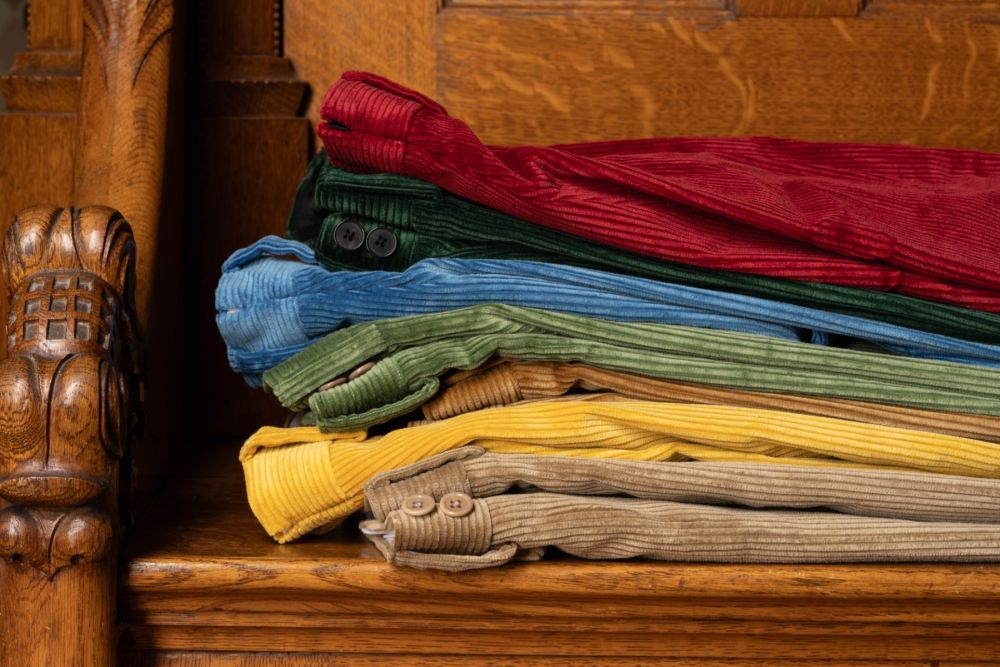 Casually stacked Fort Belvedere Corduroy pants in multiple colors, including the Garnet Red one