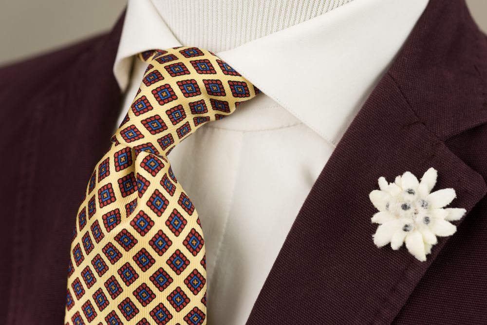 Madder Print Silk Tie in Yellow with Red, Blue and Orange Diamond Pattern paired with Edelweiss Boutonniere  - Fort Belvedere