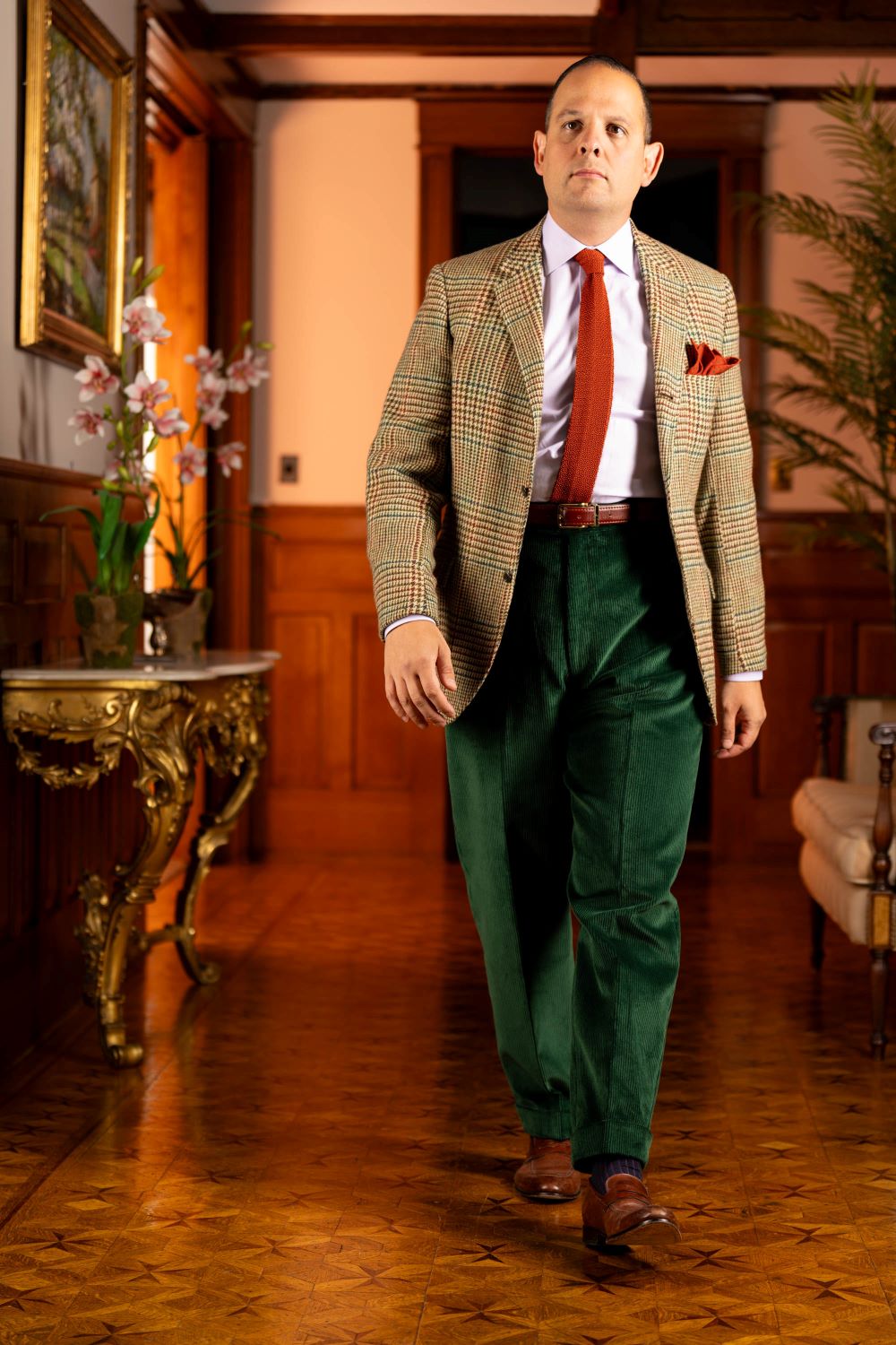 Sven Raphael Schneider modelling the Stancliffe Corduroy trousers in British Racing Green with a bold Prince of Wales Check Tweed Sport coat and orange knit tie and wool challis pocket square in orange with green Polka dots